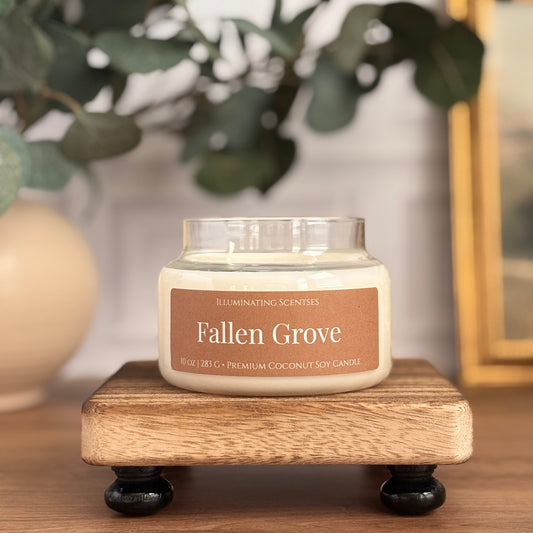 Fallen Grove jar candle by Illuminating Scentses with the lid removed, displayed on a wooden stand.