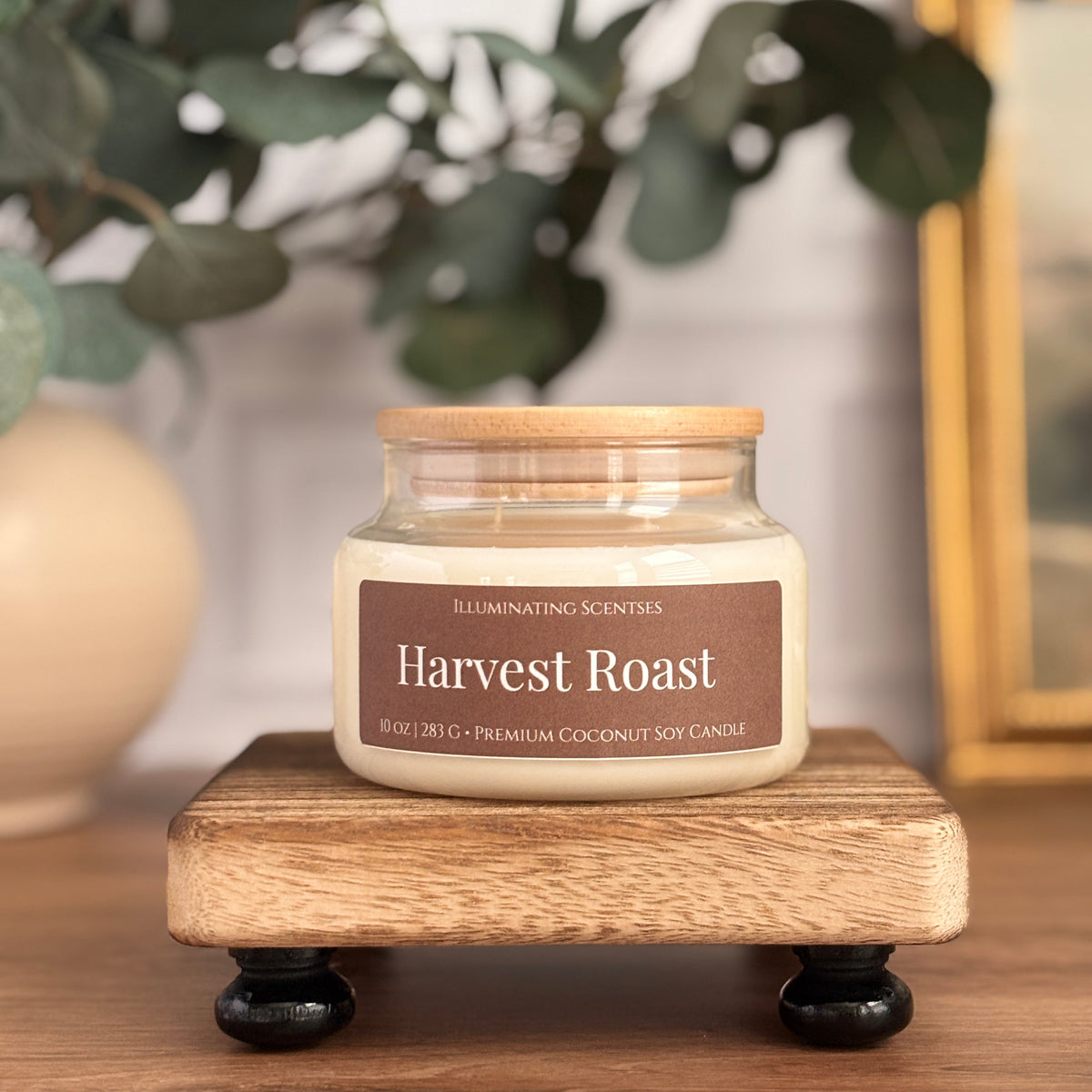 Harvest Roast jar candle by Illuminating Scentses with the lid on, displayed on a wooden stand.