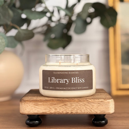 Library Bliss jar candle by Illuminating Scentses with the lid removed, displayed on a wooden stand.