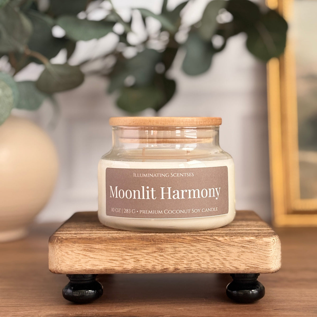 Moonlit Harmony coconut soy candle by Illuminating Scentses in an apothecary jar on a wood stand